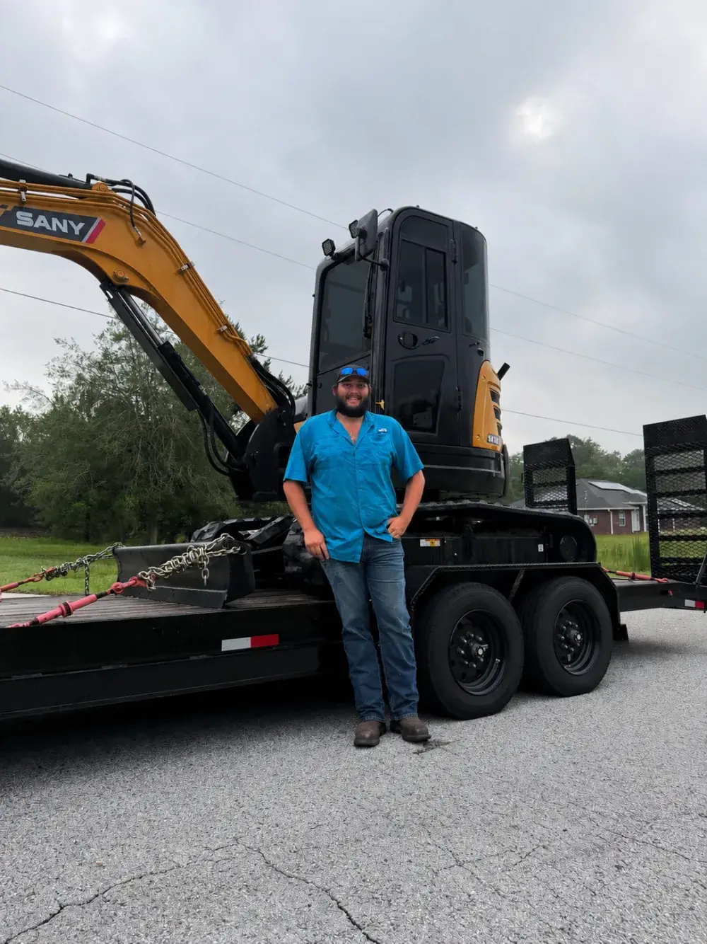 Zach Faller standing in front of Falcon Excavation equipment