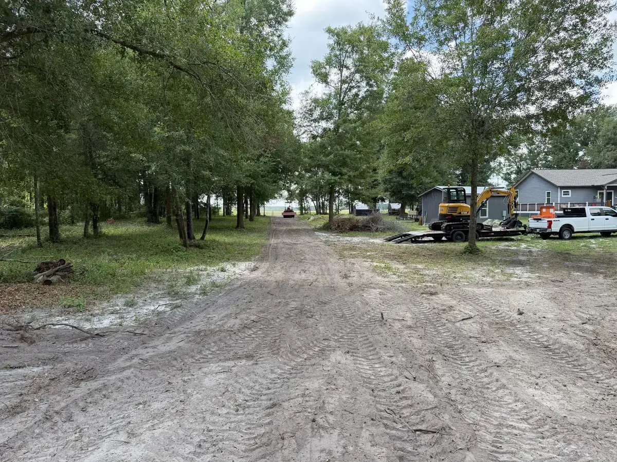 Sandy access route between trees with equipment beside the drive.